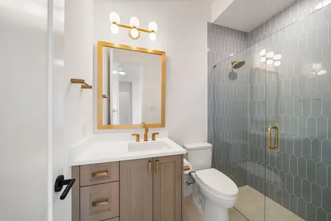 a bathroom with a toilet a sink a mirror and vanity