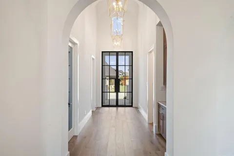 view of a hallway with wooden floor and a chandelier