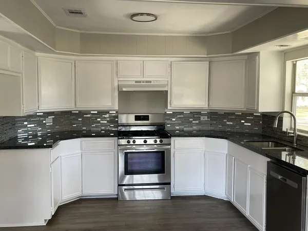 a kitchen with stainless steel appliances granite countertop a sink stove and cabinets