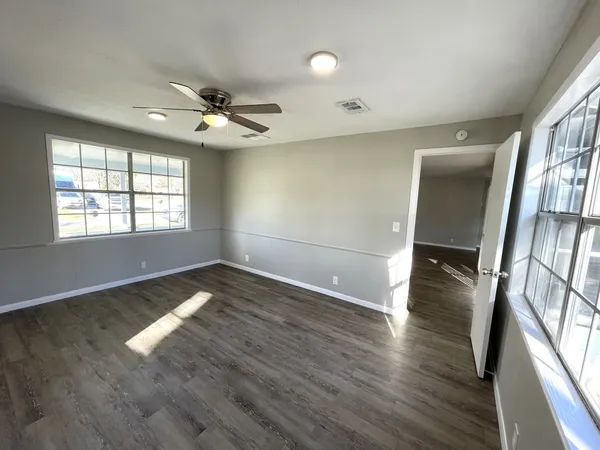 an empty room with wooden floor and windows