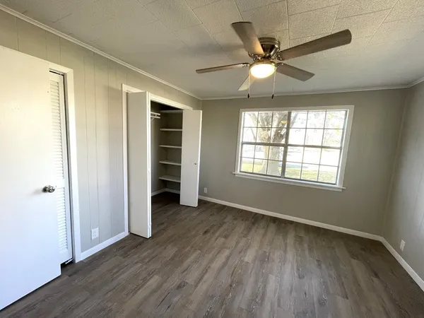 a view of an empty room with a window and wooden floor