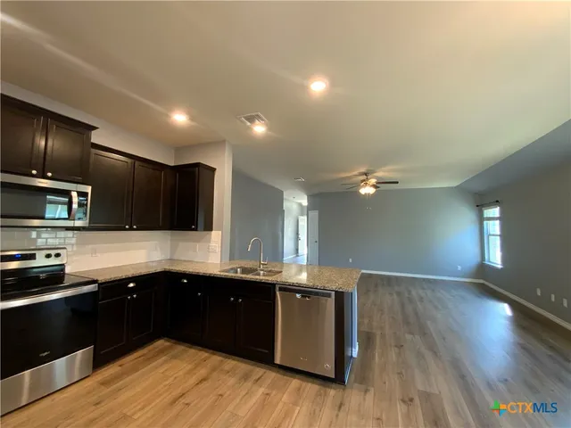 a kitchen with stainless steel appliances kitchen island granite countertop a sink counter space and cabinets