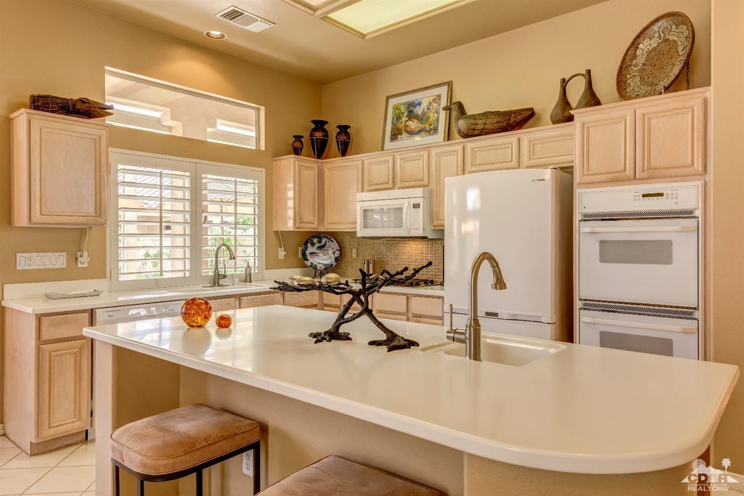 78087 Hunter Point Road Palm Desert, CA 92211 - Photo 16 of 37 a kitchen with white cabinets and black stainless steel appliances