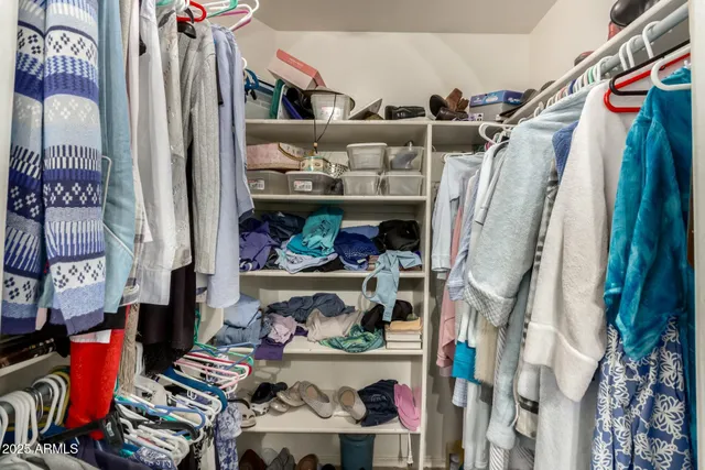 a view of walk in closet with clothes and shoes
