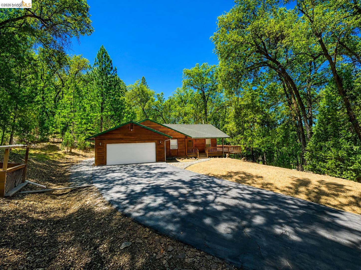 21181 Phoenix Lake Road Sonora, CA 95370 - Photo 2 of 34 Wood-sided residence with an attached garage, covered front porch, and a paved driveway