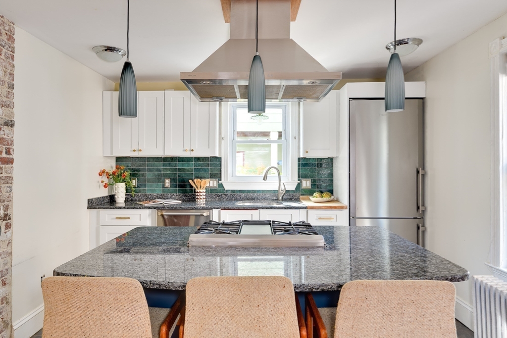 33 Line Street, Unit 1 Cambridge, MA 02138 - Photo 11 of 22 a kitchen with stainless steel appliances granite countertop a table chairs and a refrigerator