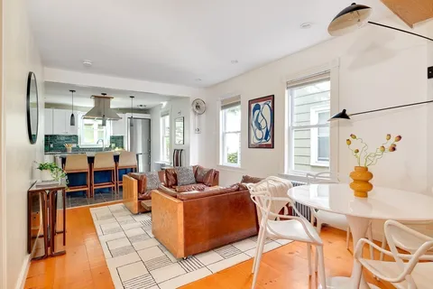 a living room with fireplace furniture and a dining table with wooden floor