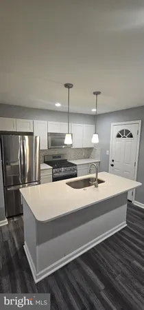 a large kitchen with kitchen island a sink stainless steel appliances and white cabinets