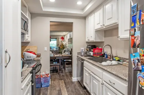 a kitchen with granite countertop a sink cabinets and appliances