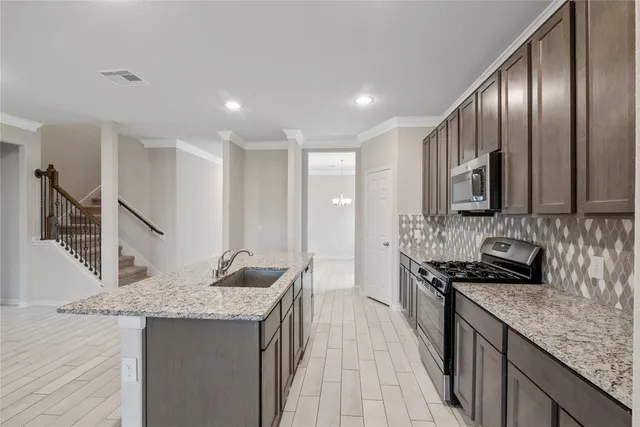 a kitchen with granite countertop stainless steel appliances sink stove microwave and cabinets