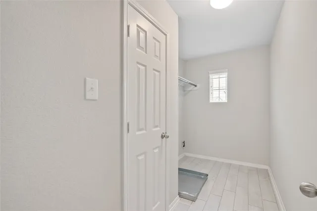 a view of a hallway with wooden floor and a bathroom
