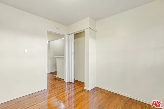 a view of a hallway with wooden floor and a bathroom