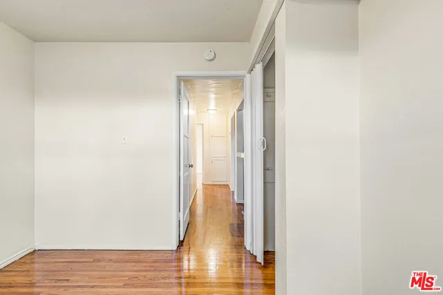 a view of empty room with wooden floor and fan