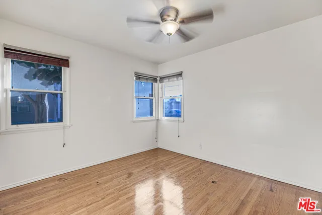 a view of empty room with wooden floor and fan