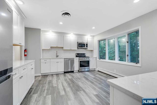32 Rock Road Englewood Cliffs, NJ 07632 - Photo 4 of 30 a large kitchen with stainless steel appliances granite countertop a stove a sink dishwasher a refrigerator white cabinets and wooden floor next to a window