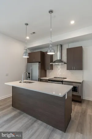 a kitchen with stainless steel appliances granite countertop a sink a stove and a wooden floor