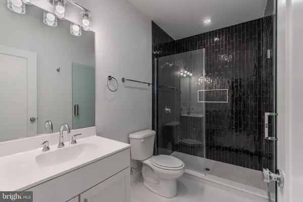 a bathroom with a shower sink vanity mirror and toilet