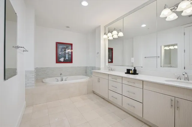 a spacious bathroom with a double vanity sink mirror and a bathtub