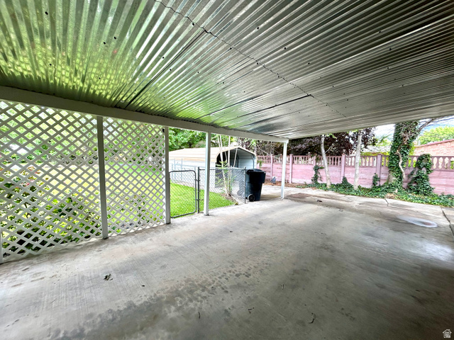 441 South 400 East Payson, UT 84651 - Photo 31 of 39 Covered concrete patio featuring a corrugated metal roof, white lattice privacy screen, and partial chain-link fencing