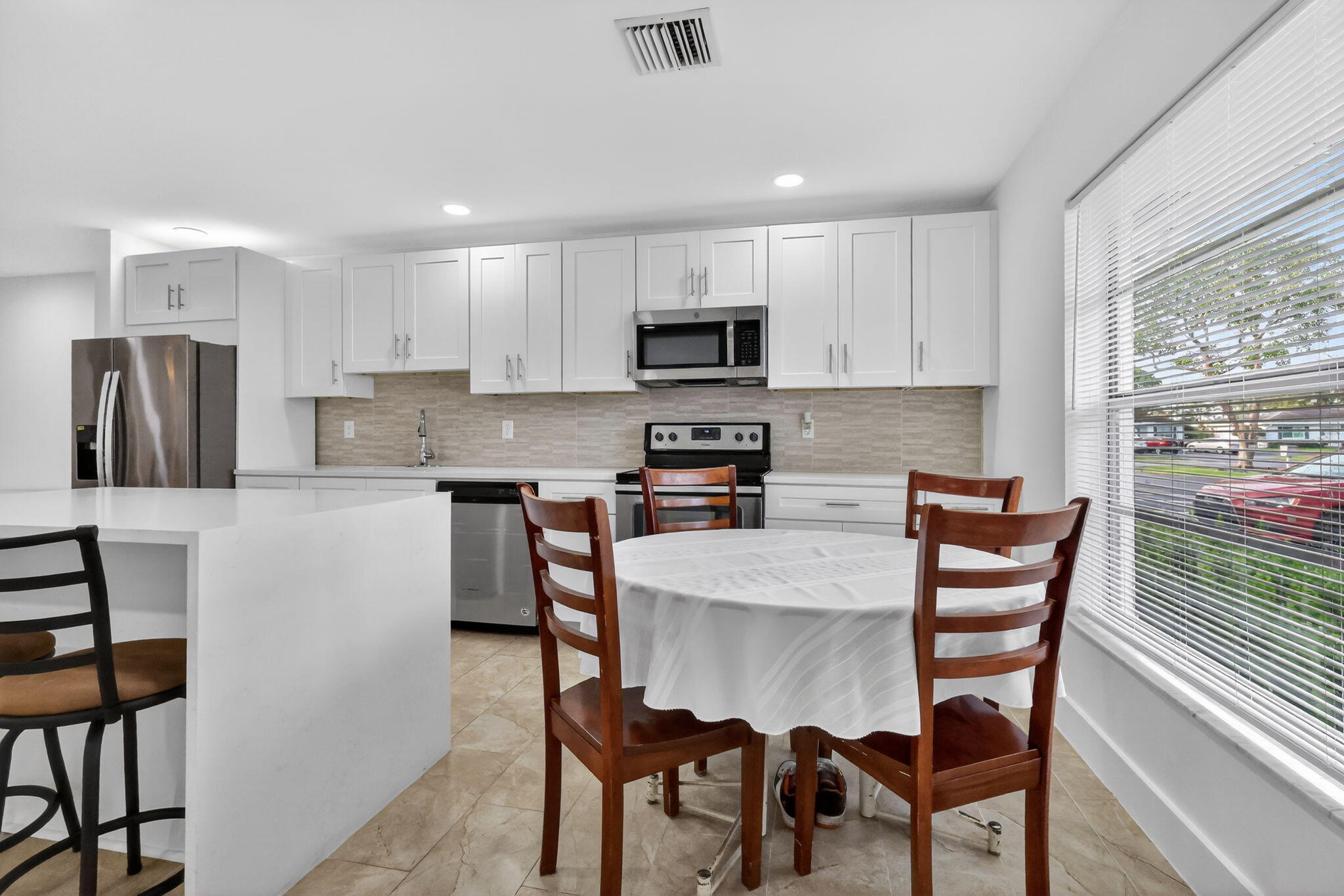 5093 Privet Place, Unit A1 Delray Beach, FL 33484 - Photo 11 of 54 a kitchen with stainless steel appliances granite countertop a dining table chairs refrigerator a sink and dishwasher