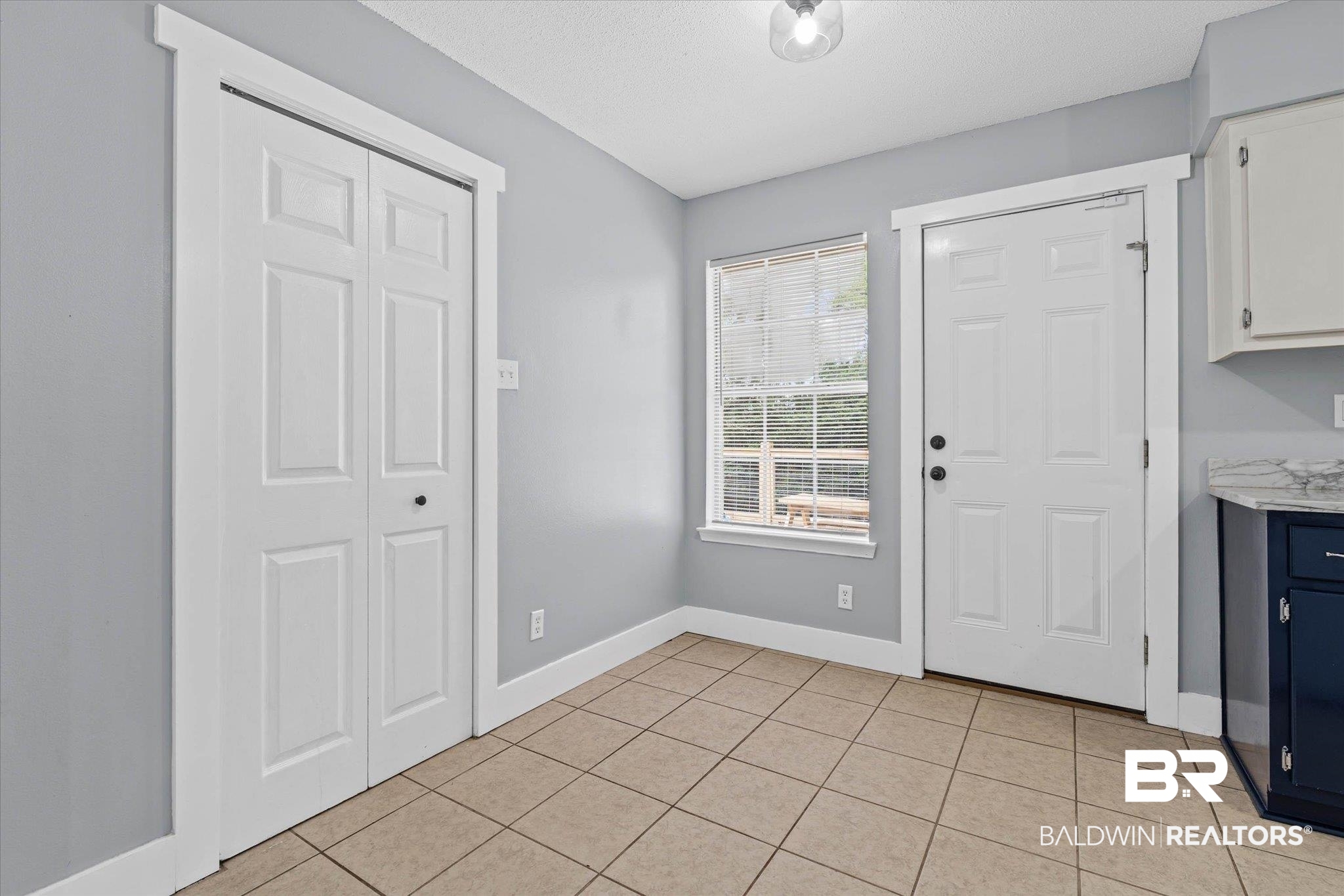 1849 Ranch House Drive Semmes, AL 36575 - Photo 6 of 23 Doorway to outside featuring tile patterned flooring and a textured ceiling