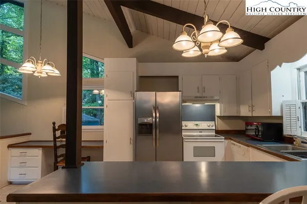 a kitchen with stainless steel appliances a large counter top a stove a chimney a sink and a refrigerator