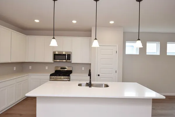 a view of a kitchen with kitchen island a sink stainless steel appliances and cabinets