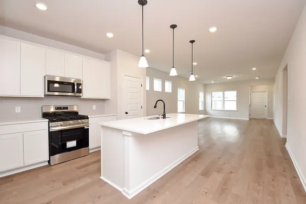 a kitchen with stainless steel appliances kitchen island granite countertop a sink a stove and a wooden floors