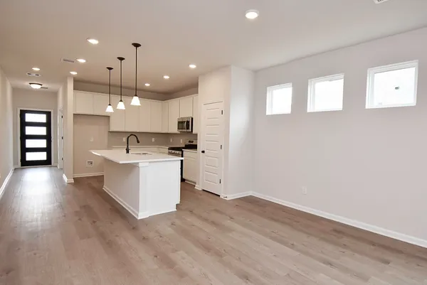a large white kitchen with a large counter top a sink stainless steel appliances and cabinets
