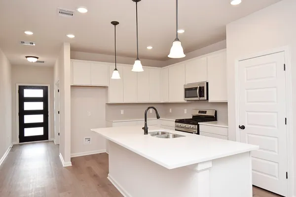 a kitchen with kitchen island a sink and a stove top oven with wooden floor