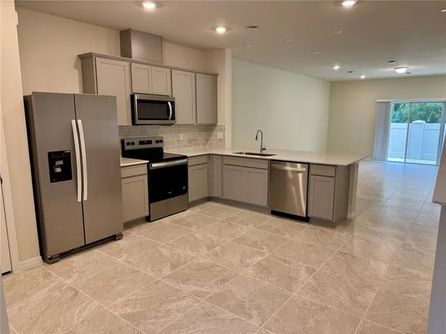 a kitchen with stainless steel appliances granite countertop a refrigerator a stove top oven a sink and dishwasher