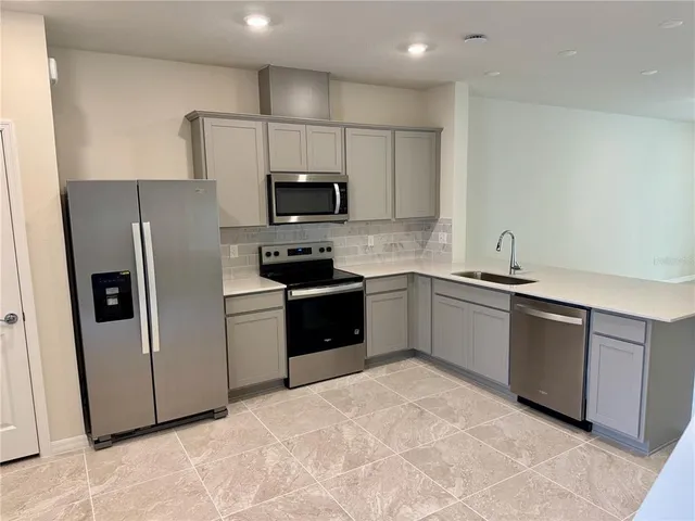 a kitchen with stainless steel appliances a refrigerator sink and microwave