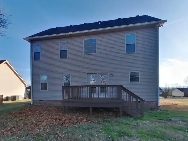 a view of a house with a yard and wooden deck