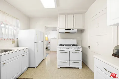 a kitchen with white cabinets and white appliances