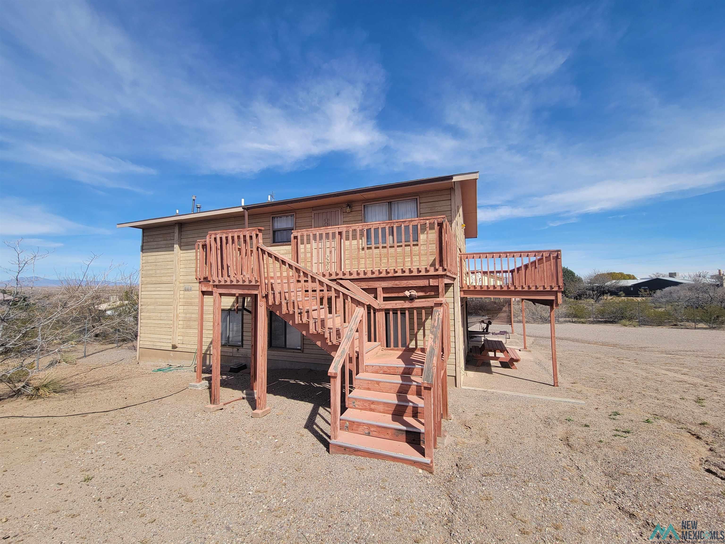 501 Springland Boulevard Elephant Butte, NM 87935 - Photo 1 of 38 Two-story home featuring exterior siding, multiple exterior staircases, and an upper-level deck with wooden railings