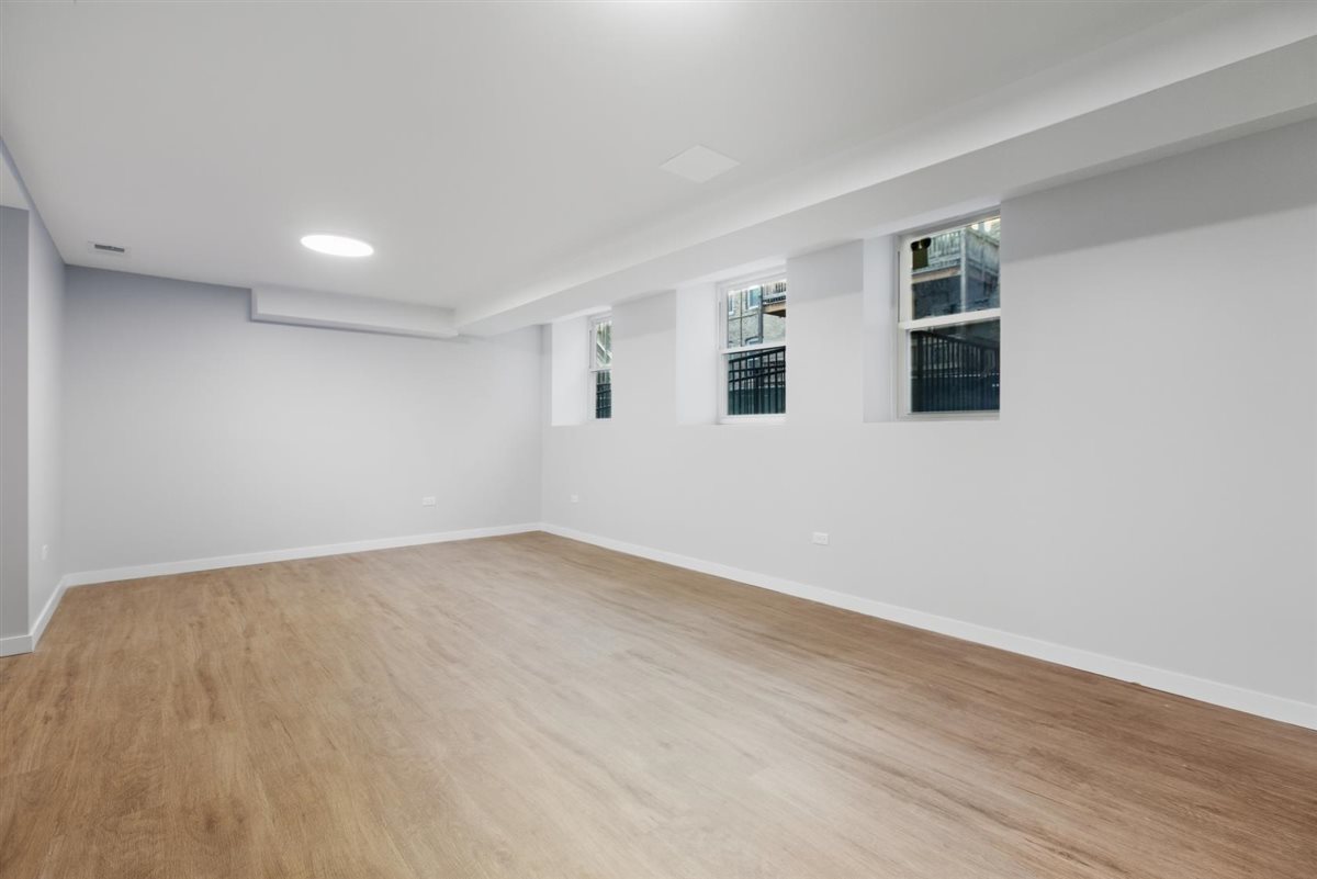 4700 North Racine Avenue, Unit 106 Chicago, IL 60640 - Photo 7 of 10 a view of an empty room with wooden floor and a window