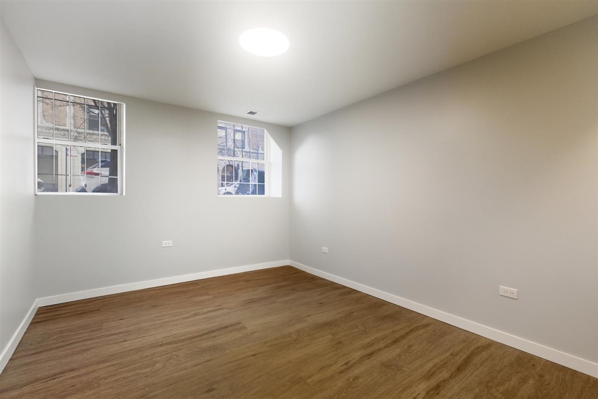 4700 North Racine Avenue, Unit 106 Chicago, IL 60640 - Photo 9 of 10 a view of an empty room with wooden floor and a window