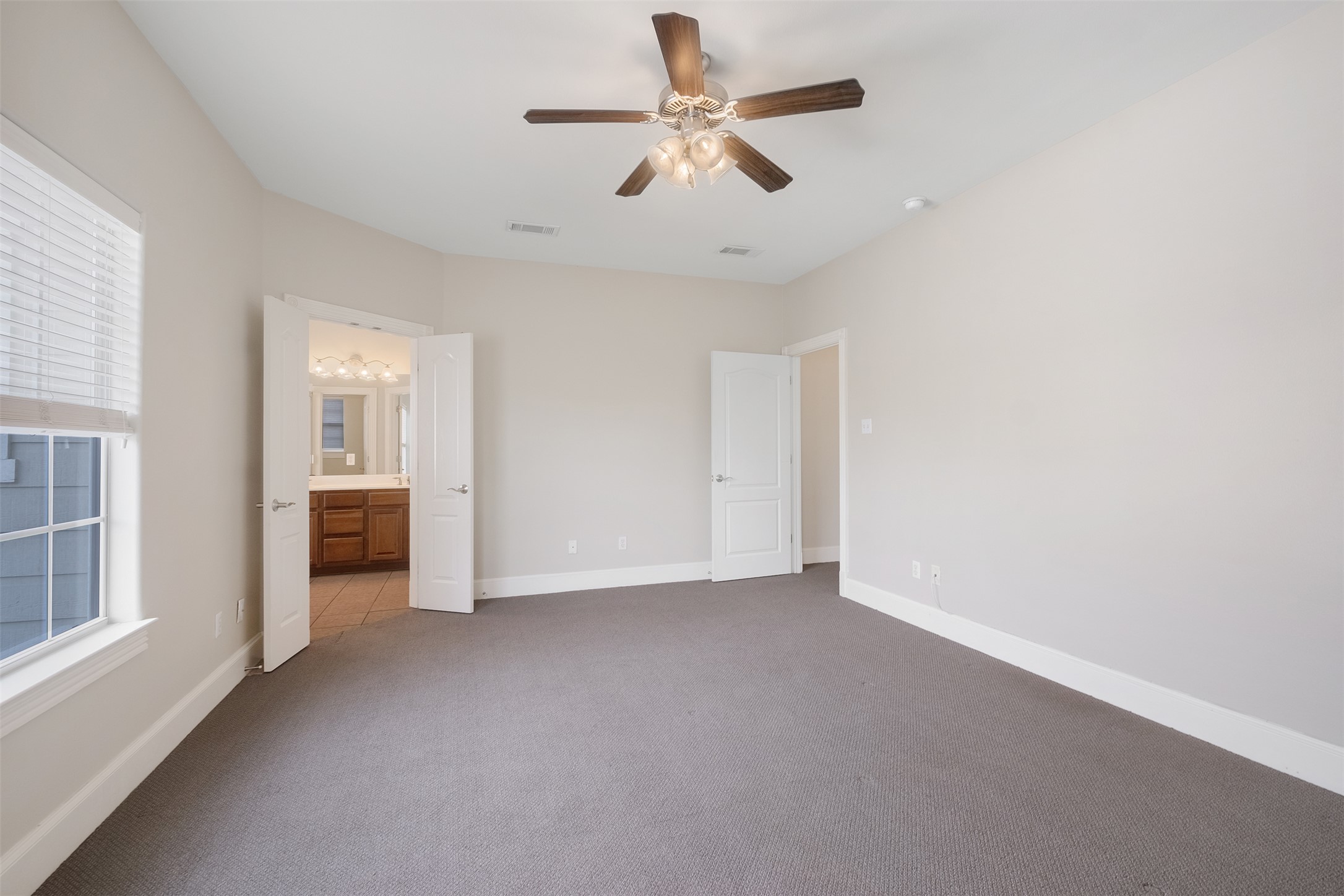 6715 Windrift Way, Unit 8 Austin, TX 78745 - Photo 14 of 24 A spacious chamber awaits, complete with a ceiling fan for comfort and an adjacent private bathroom.