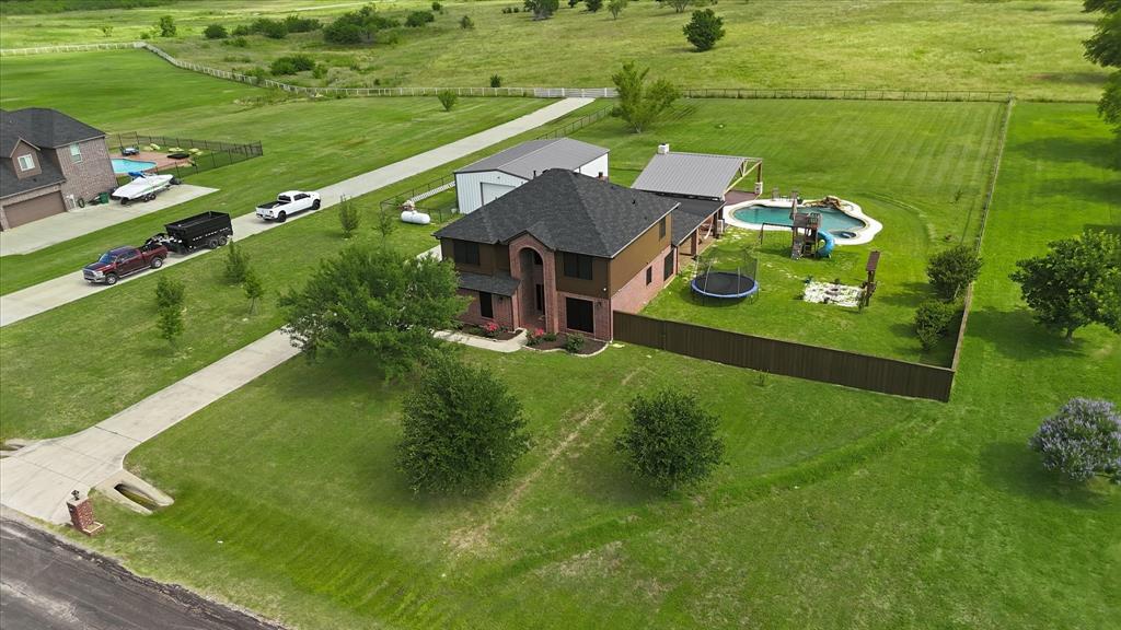 430 Ridgecrest Place Sanger, TX 76266 - Photo 37 of 40 Expansive property featuring a two-story residence with a dark shingle roof, an attached garage, and a separate outbuilding with a light-colored roof