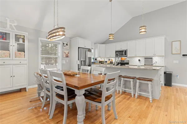 a kitchen with stainless steel appliances kitchen island granite countertop a table chairs and a refrigerator