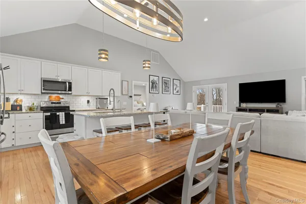 a dining room with kitchen island furniture a flat screen tv and kitchen view