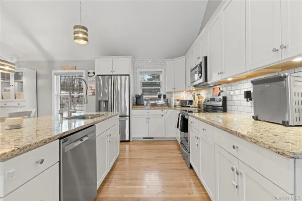 a large white kitchen with granite countertop lots of counter top space and stainless steel appliances
