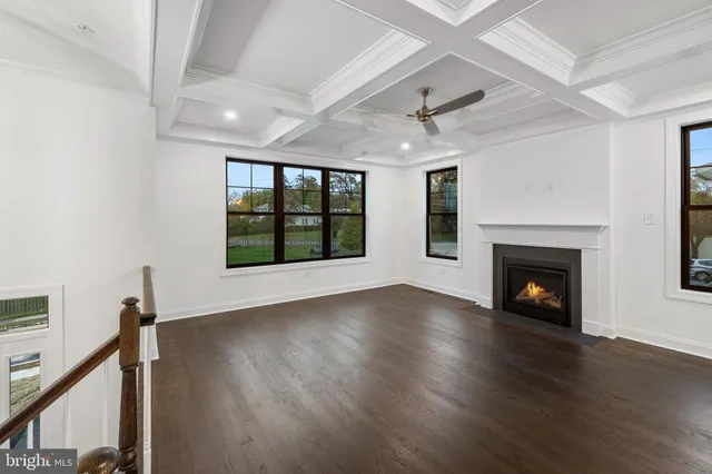 a view of an empty room with wooden floor fireplace and a window