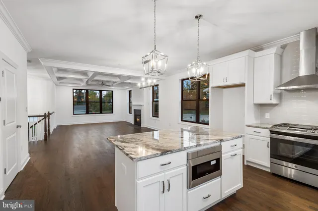 a kitchen with stainless steel appliances granite countertop a stove and white cabinets with wooden floor
