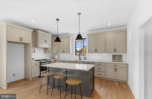 a kitchen with stainless steel appliances granite countertop a sink a stove a refrigerator and island with wooden floor