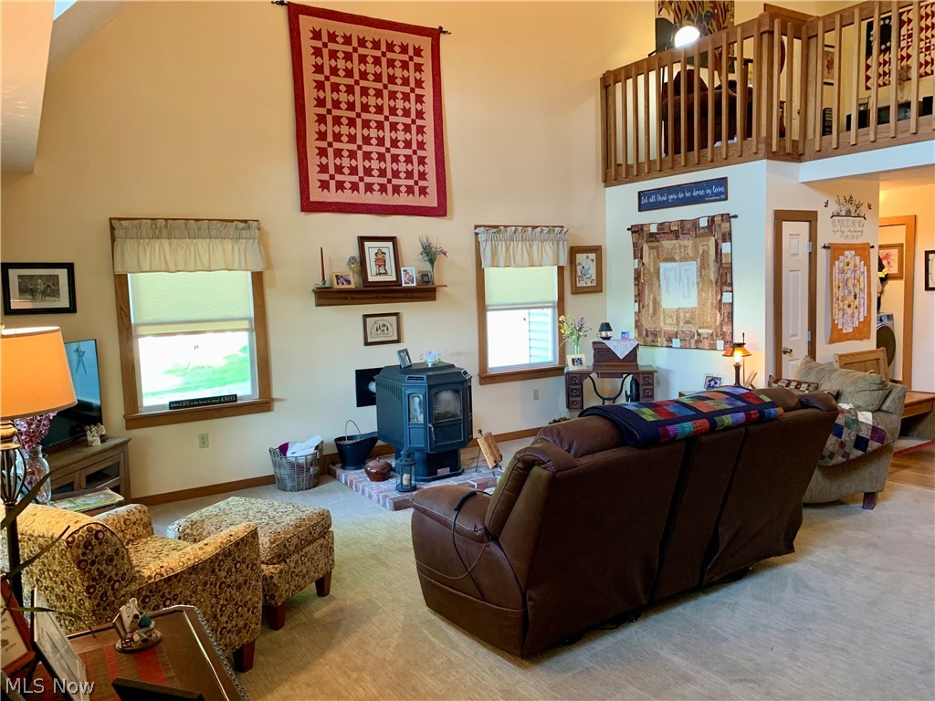 373 South Ridge Road West Conneaut, OH 44030 - Photo 11 of 50 Living room featuring plenty of natural light, a towering ceiling, and a wood stove