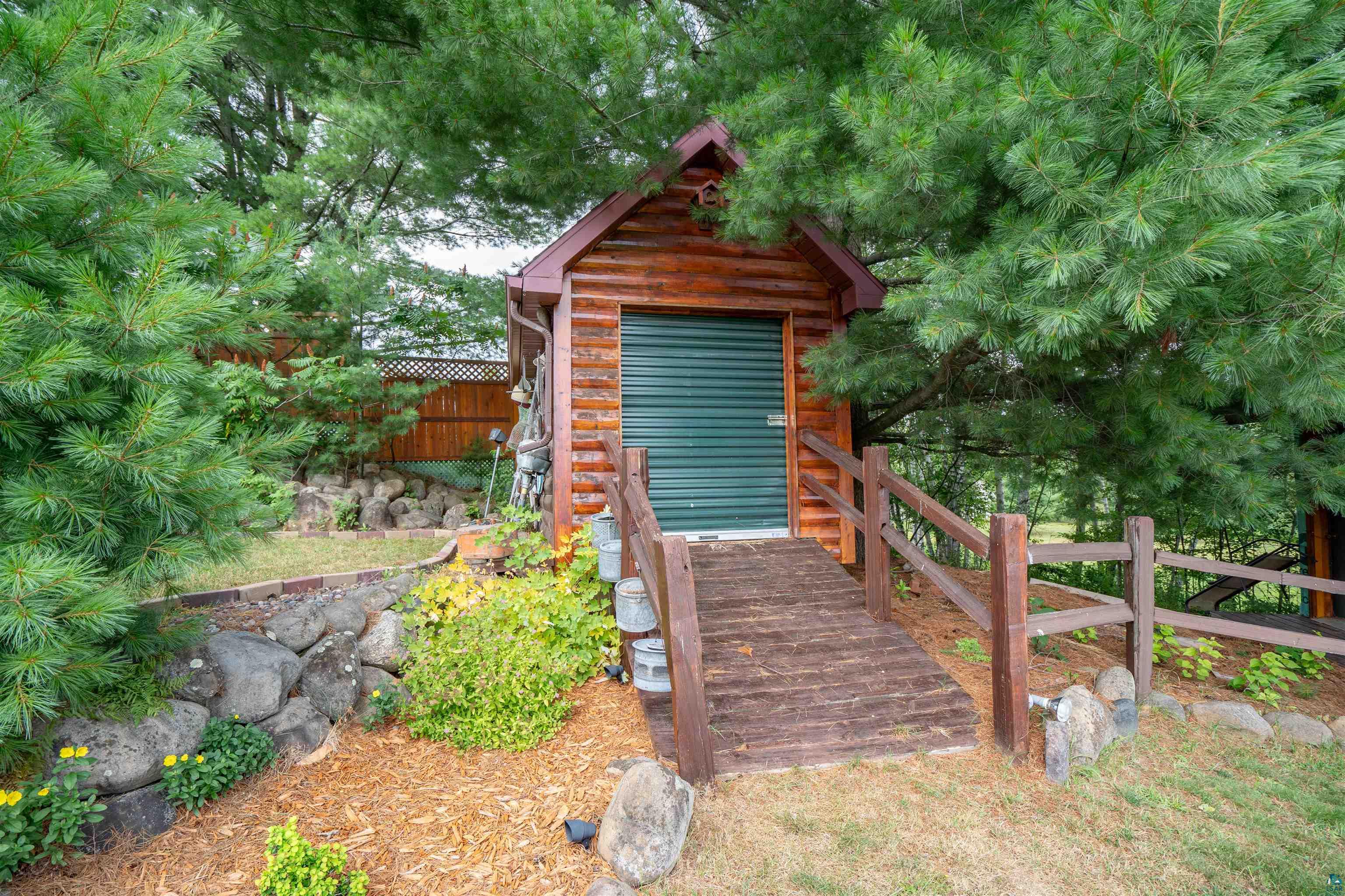 11911 East Rowe Road Lake Nebagamon, WI 54849 - Photo 29 of 61 Log-sided outbuilding featuring a green roll-up door and a wooden access ramp