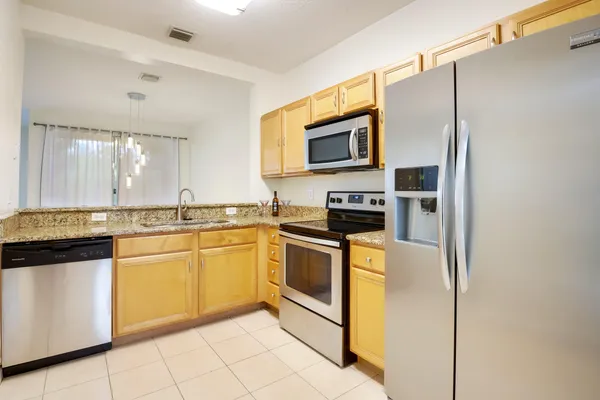 a kitchen with stainless steel appliances granite countertop a refrigerator a stove top oven and sink