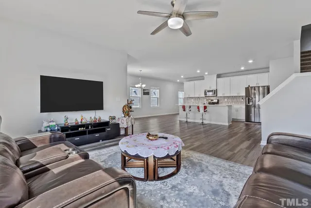 a kitchen with stainless steel appliances granite countertop a sink dishwasher and a refrigerator with wooden floor