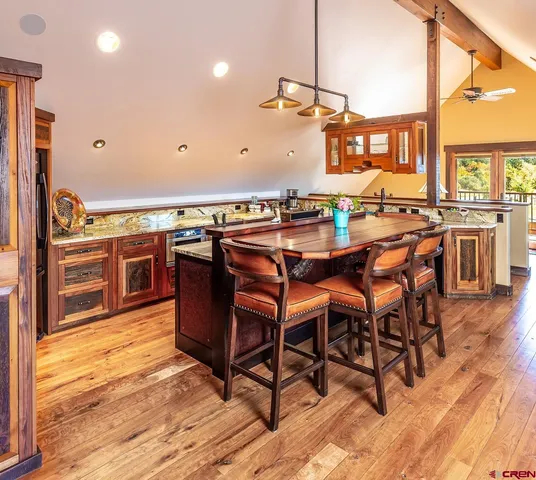 a kitchen with stainless steel appliances granite countertop a table chairs stove and wooden floor